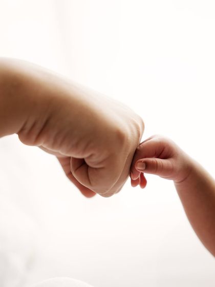 A tiny fist bump between a newborn and a parent. A fun and modern take on the classic hand-holding shot.