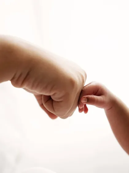 A tiny fist bump. A playful and sweet way to capture the bond between a parent and their new little buddy.
