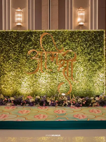 A modern and chic photo backdrop featuring a green wall with a golden "Shree" motif. This is an example of personalized and contemporary decor.