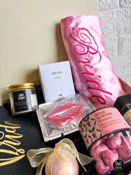 A specially curated hamper for the bride, including a satin 'Bride' robe, a 'Love Story' candle, rose almond dragees, and a pampering lip mask.