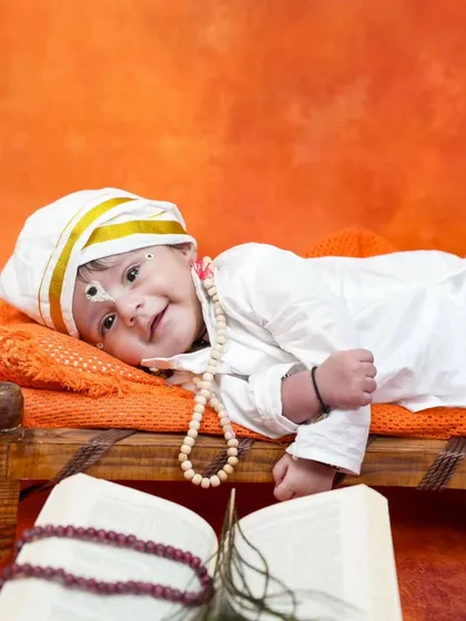 A sweet smile from our little devotee, resting on a miniature cot in the Vitthal theme setup. The simplicity of this shot highlights the baby's joyful expression.