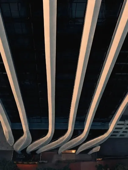An abstract, top-down view of the illuminated facade fins, highlighting the rhythm and pattern of the calligraphic design.