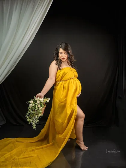 A pop of sunshine against a dramatic black backdrop. This portrait uses a vibrant yellow gown and a basket of fresh flowers to create a look that is both bold and beautiful.