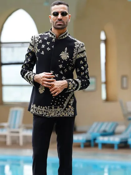 An exceptionally detailed black Jodhpuri suit with all-over floral and paisley embroidery in gold and silver thread. This is a masterpiece of craftsmanship for a truly royal look.