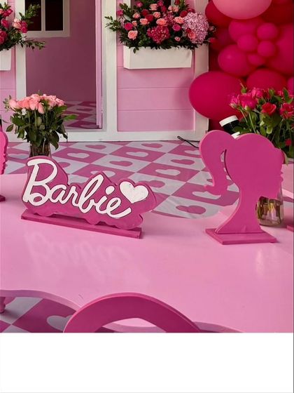Themed table signs with the iconic Barbie logo and silhouette add a polished touch to the decor.