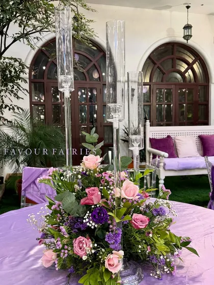 A beautiful floral centerpiece for the enchanted garden party. We used a mix of pink and purple flowers with tall glass candle holders to add elegance to the tables.