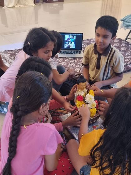 Children working together, both in-person and virtually, to adorn the Buddha statue. This shows how our community connects, no matter the distance.
