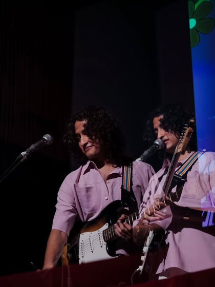 A guitarist from the band Mannequin Disorder on stage, bathed in pink light. The photo showcases the cool, retro aesthetic of the bands that perform at our events.
