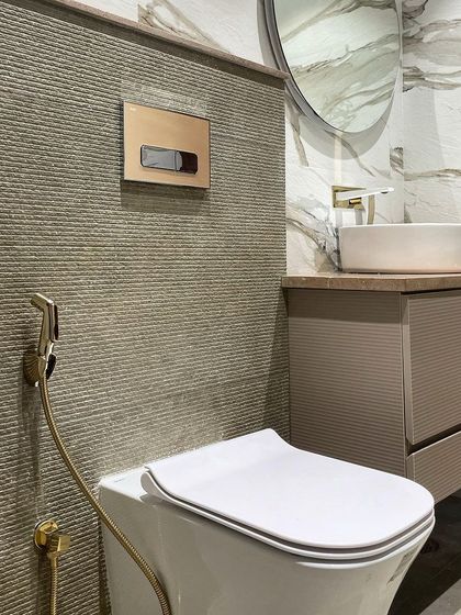 A close-up of the material combination in this bathroom: the grooved texture of the accent wall, the smooth marble-look tile, and the elegant brushed gold fixtures.