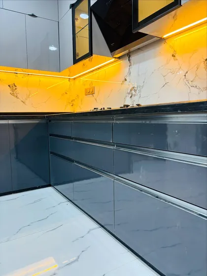 Detail of a handleless modular kitchen design. The G-profile channels on these high-gloss grey drawers create a clean, minimalist look while ensuring easy operation.