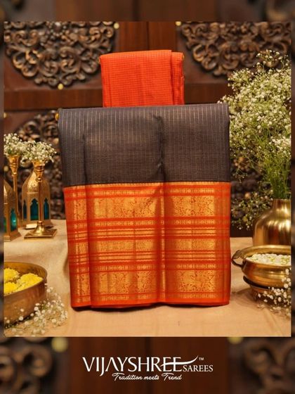 A sophisticated black Kanjivaram with an orange korvai border and intricate gold zari work.