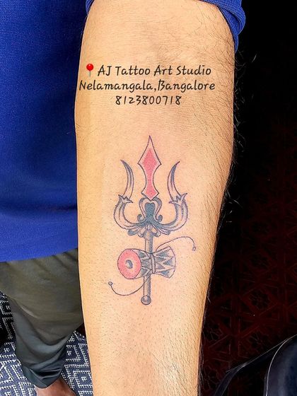 A Trishul and Damaru tattoo with red accents, adding a pop of color to this spiritual piece.