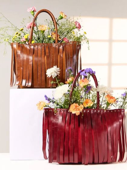 Our Tassel Totes in rich brown and red, filled with flowers. These bags are designed to carry your life with style and ease.
