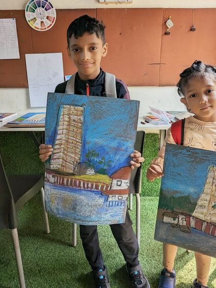 Two students with their fantastic paintings of a temple. This project involved learning about architecture and using oil pastels to create texture.