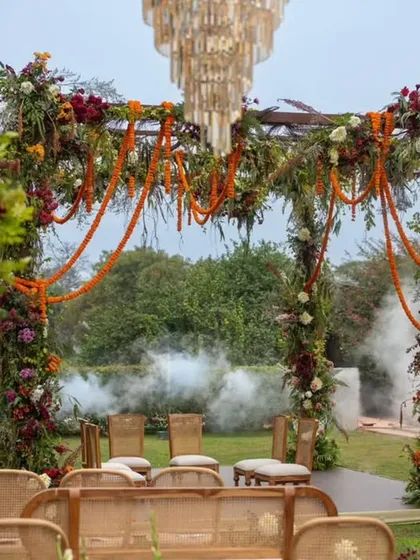 A dramatic and romantic mandap moment, with smoke adding a touch of mystique to the lush floral arch and chandelier. Every detail is crafted for a cinematic feel.