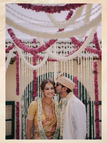 A sweet kiss on the cheek under the beautiful floral mandap.