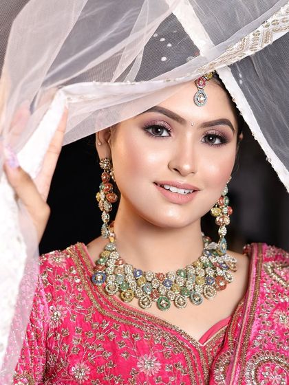 A dreamy look for a bride in a bright pink lehenga. The makeup is soft and romantic, with a focus on glowing skin and pretty pink tones.
