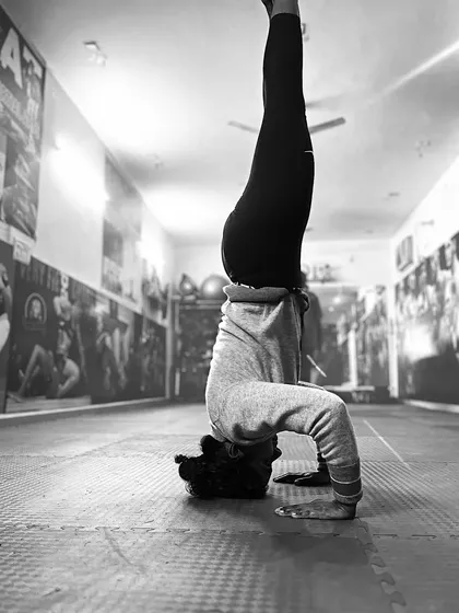 Balance is not given, it is earned. This student demonstrates a perfect headstand, a result of consistent practice in our bodyweight gymnastics training. This black and white shot captures the intense focus and core strength required to master such inversions.