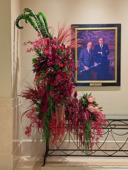 The complete red arrangement, standing elegantly beside a portrait. My designs are always mindful of their environment, intended to complement and elevate the existing space.