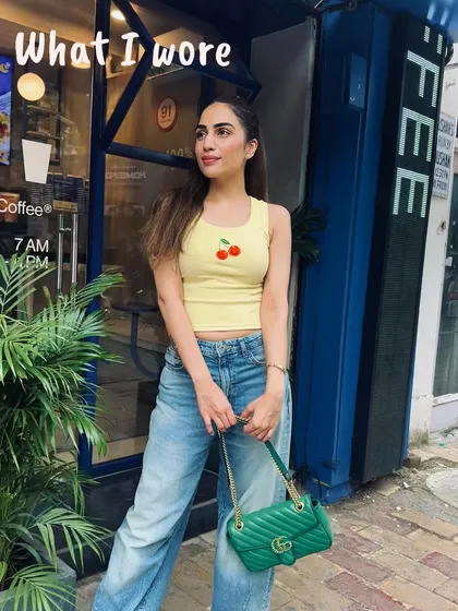 A cute and casual coffee run outfit. This yellow tank top with a cherry detail adds a playful touch to a simple pair of blue jeans.