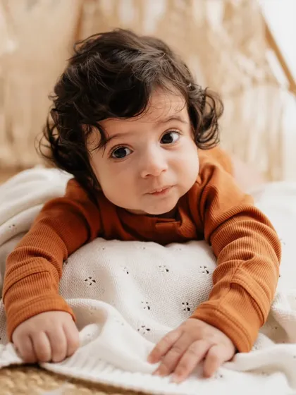 A classic tummy time pose. This is a key milestone for infants around 3-4 months, and this little one is showing off his strength.