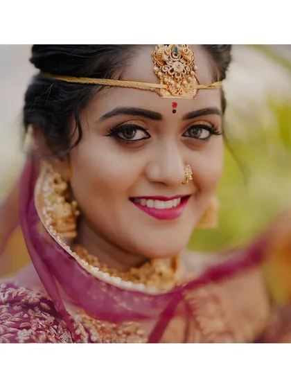 A bride's smile holds all the light of her special day. This portrait captures the happiness and anticipation of a South Indian bride, highlighting the intricate details of her jewelry and the genuine glow of her excitement.