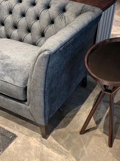 A detail of a classic sofa with tufted upholstery, paired with a simple wooden side table.
