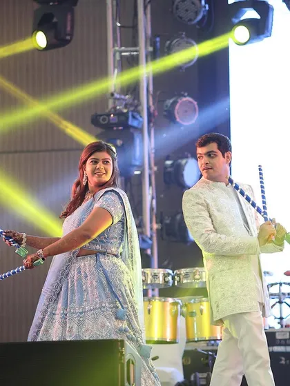 The happy couple enjoying a dandiya dance on stage, a highlight of their energetic and fun-filled Sangeet night.