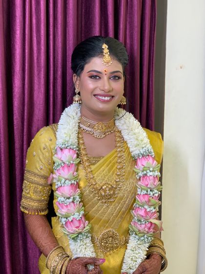 This bride is glowing in her golden yellow Muhurtham saree. The drape is kept classic and neat to let the saree's colour and the temple jewellery shine.