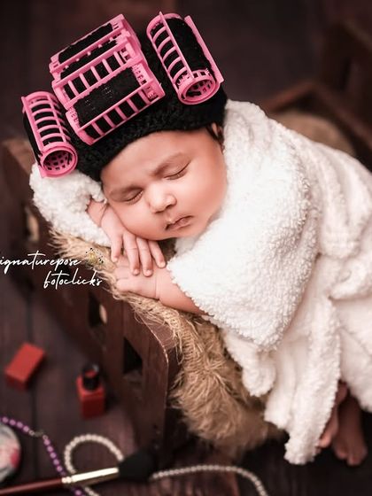A close-up portrait of the sleeping baby with hair rollers, highlighting the adorable and funny contrast.