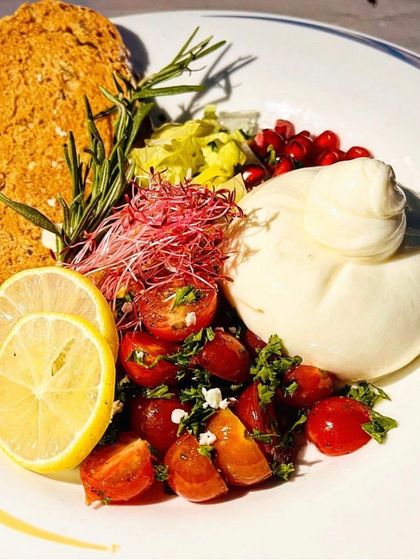 This dish is a celebration of fresh Italian flavours. A luscious burrata is paired with a bright cherry tomato and herb salad, zesty lemon, and a sprig of rosemary, served with toasted bread for a complete and satisfying plate.