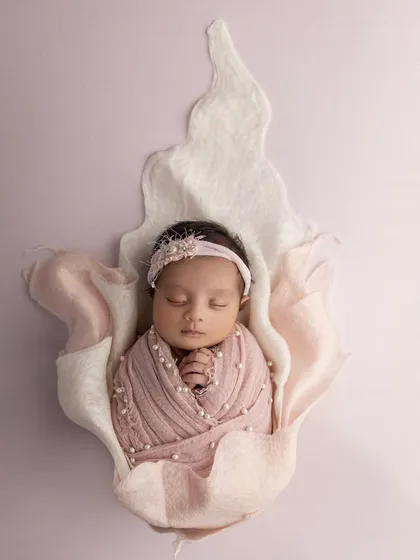A closer view of the baby blooming in the flower prop, focusing on her peaceful face and the delicate textures of the setup.