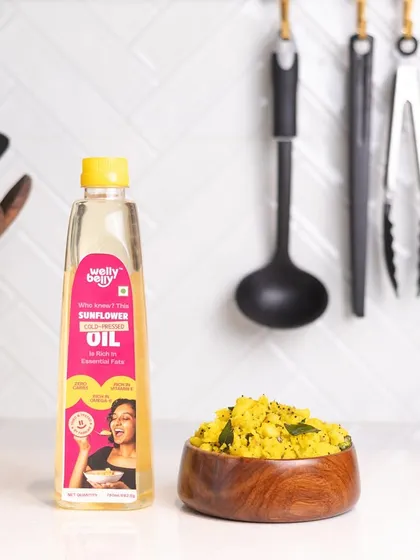A clean and bright product shot of sunflower oil next to a bowl of poha, the dish it helps create. This contextualizes the product and gives the customer a usage idea.