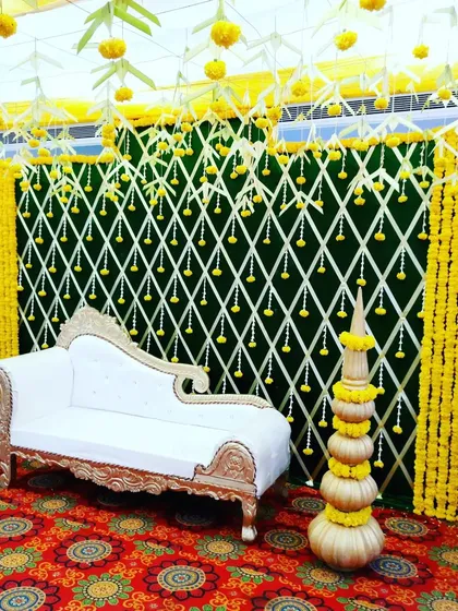 A traditional mantap stage with a white chaise lounge, decorated with yellow marigolds.