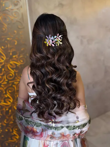 A back view of the Roka hairstyle, showing the beautiful floral accessory and the soft, cascading waves.