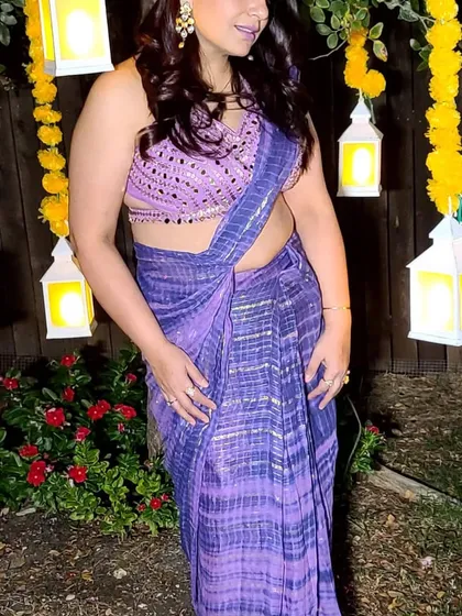 A client looking absolutely radiant in a purple ready-draped saree. The mirror-work blouse with a stylish back is the perfect complement to the shibori-style print.