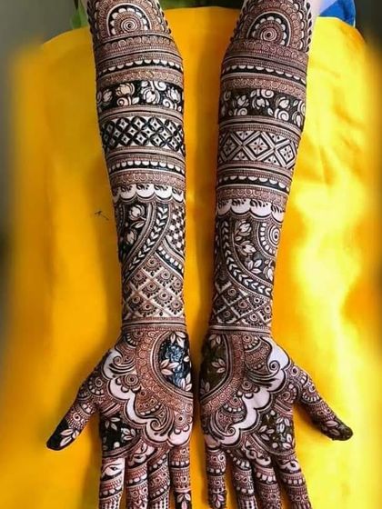A stunning example of symmetrical bridal mehndi. The intricate checkerboard patterns and bold floral bands create a captivating and balanced design across both arms.