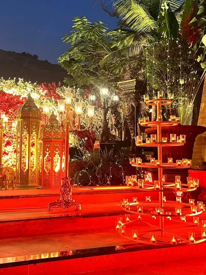 Lighting is key to creating ambiance. Here, a multi-tiered candle stand and a classic candelabra add a warm, romantic glow to the red-carpeted venue.