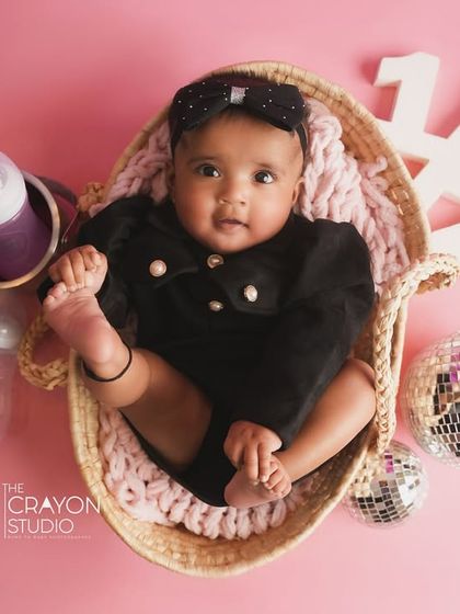An overhead shot of one of the twin girls in a basket, surrounded by disco balls and party props for their half-birthday.