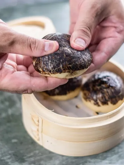 Our iconic Char Siu Pork Baos from the 'Moon House' menu, served in a traditional bamboo steamer. The unique marbled appearance hints at the rich flavor within.