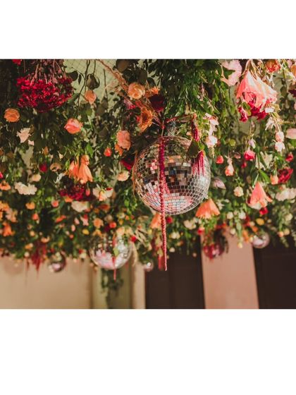 A close-up of the hanging floral installation, showing the rich textures and colors of the flowers mixed with the playful sparkle of a disco ball.