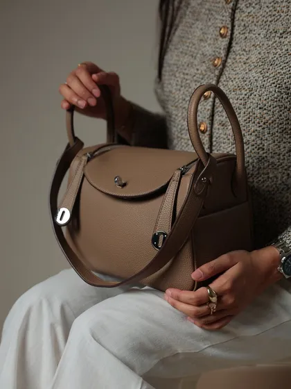 A seated view holding the Linde Large bag. This angle shows the bag's size and how the straps are attached, highlighting its practical and stylish design.