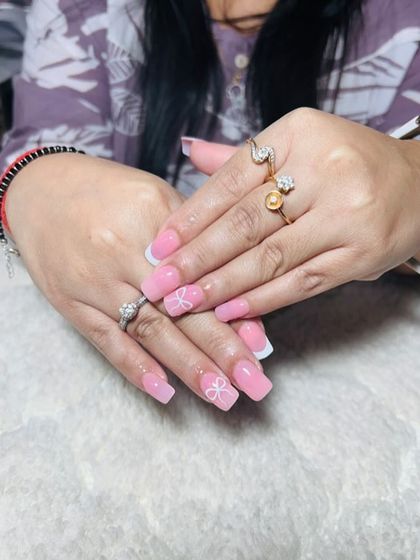 A sweet and feminine design with a solid pink base, white French tips, and delicate white bow art.