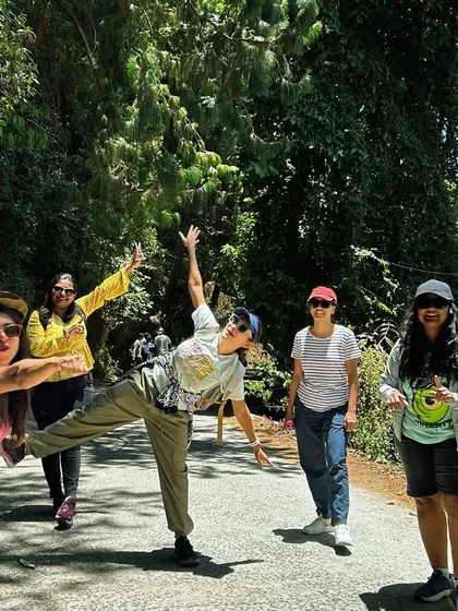 A group of women having fun on a road surrounded by tall pine trees in Kodaikanal.