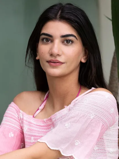 A simple, natural headshot of a model wearing a pink off-the-shoulder top. This portrait highlights a fresh, summery look that complements a beach or resort wear collection.