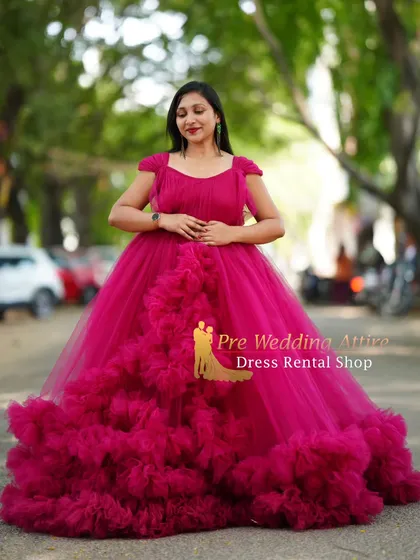 The magenta ruffled gown stands out beautifully in an urban park setting. Its voluminous skirt creates a stunning silhouette, making it a fantastic rental choice for a standout maternity photoshoot.
