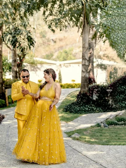 A candid moment of the couple dancing and laughing together, their yellow outfits vibrant against the green background.