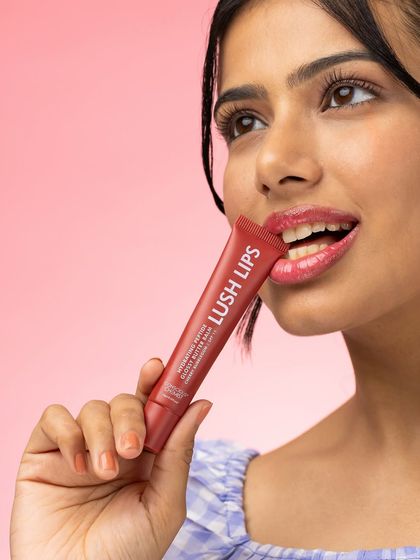 This lifestyle shot captures the playful and satisfying experience of using the lip balm. The model's expression and pose feel natural and engaging, helping customers envision themselves enjoying the product.