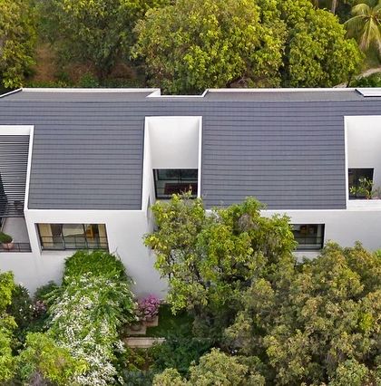 The house is designed with deep-set windows and recessed balconies, creating a play of light and shadow on the facade while providing shade and privacy for the rooms within.