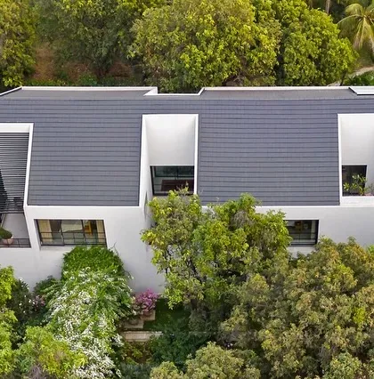 The house is designed with deep-set windows and recessed balconies, creating a play of light and shadow on the facade while providing shade and privacy for the rooms within.